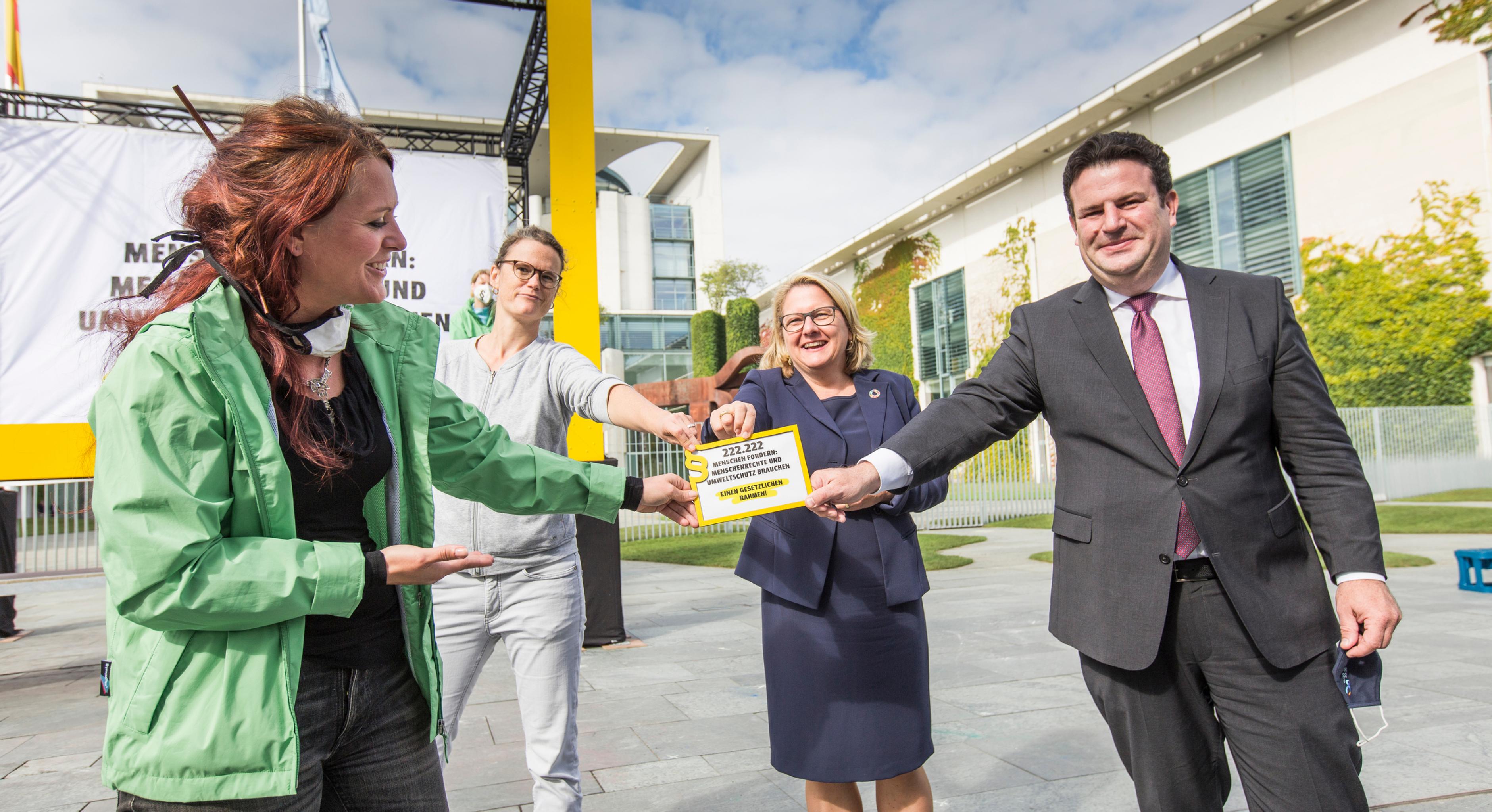 Umweltministerin Svenja Schulze und Arbeitsminister Hubertus Heil nehmen vor dem Kanzleramt ein Symbol für 222.222 Unterschriften für ein Lieferkettengesetz von zwei Aktivistinnen in Empfang