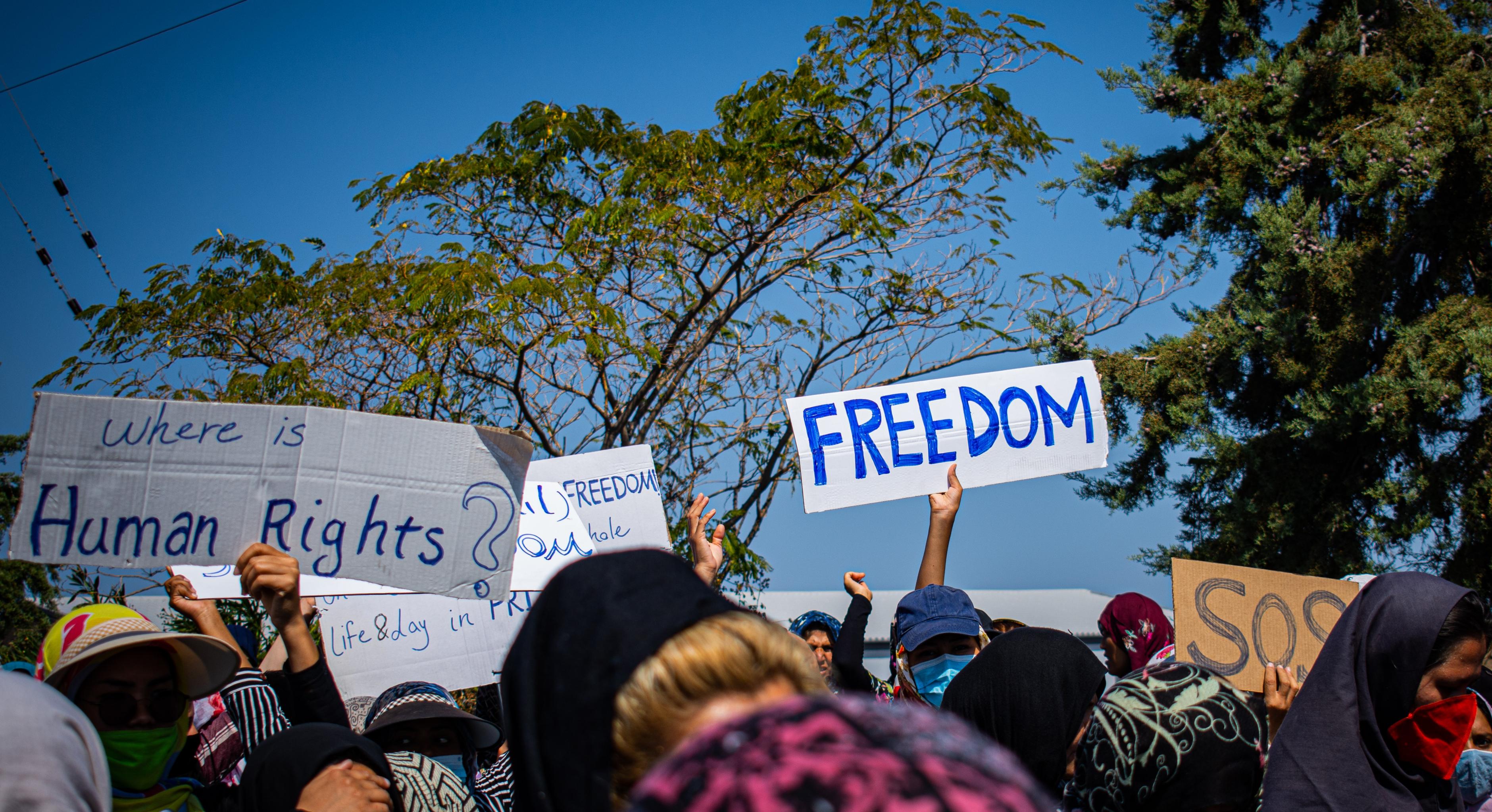 Protestierende Menschen halten Schilder hoch mit der Aufschrift "Freedom" und "Where is Human Rights?"