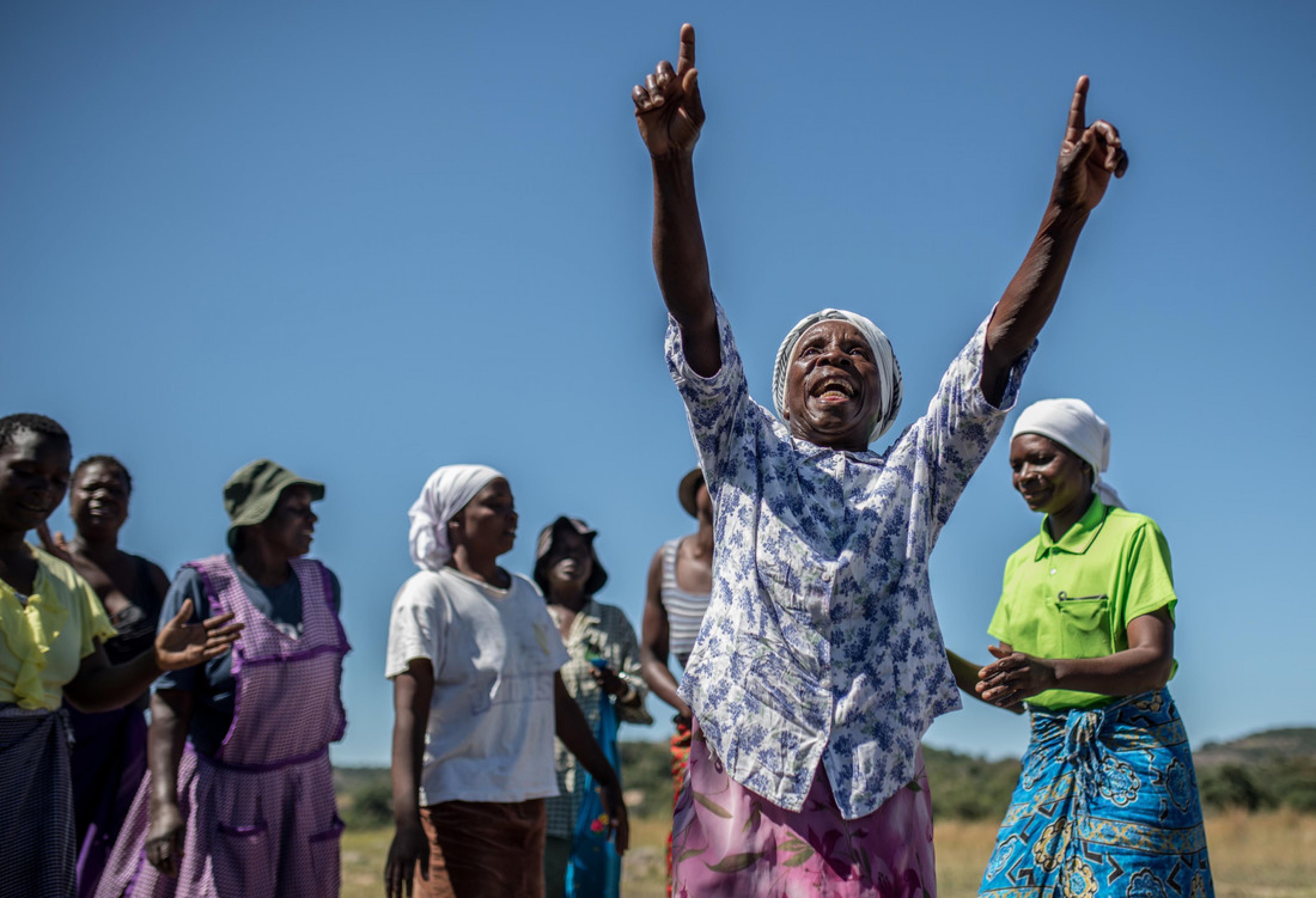 WASH: Emmily* reißt vor Freude ihre Hände in die Luft. Sie feiert die neue solarbetriebene Wasserpumpe. Dank Oxfam haben Emmily und ihre Gemeinschaft nun leichten Zugang zu Trinkwasser.