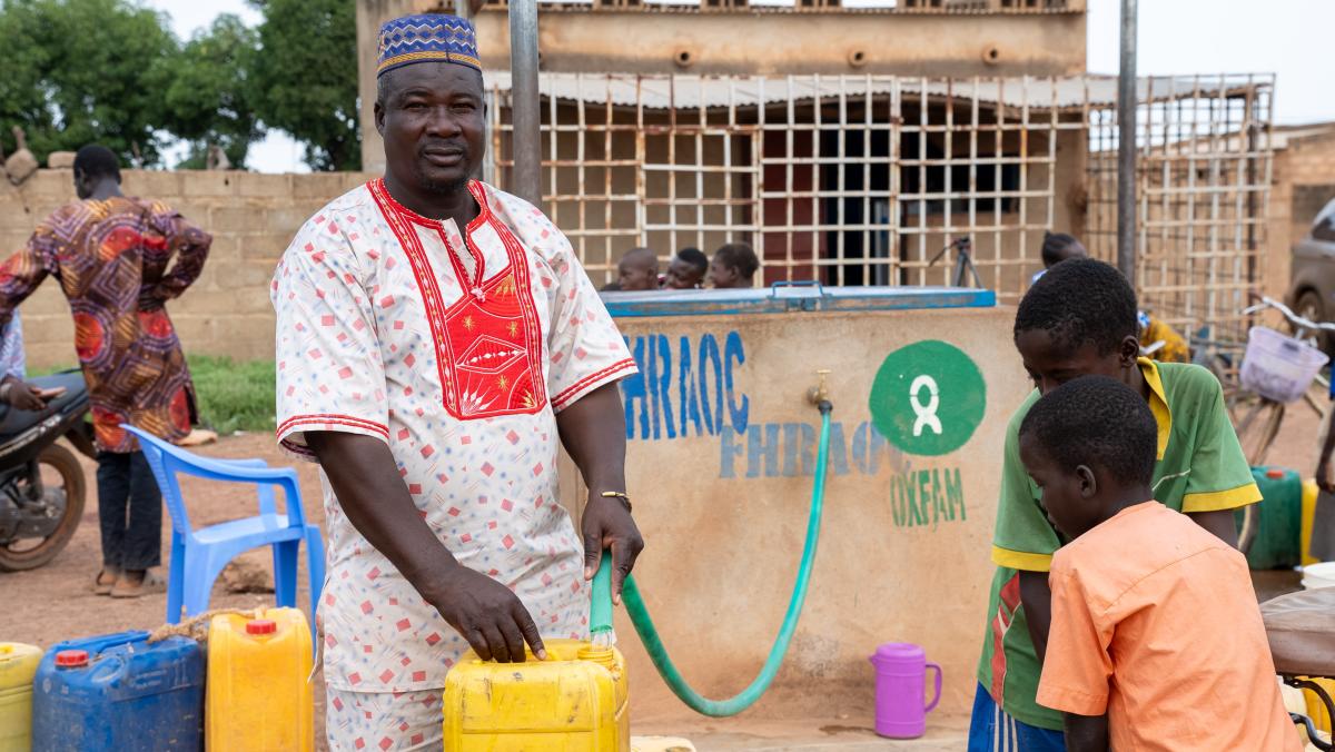 Ein Mann füllt seinen Wasserkanister auf. Dafür benutzt er den Hahn einer von Oxfam gebauten Wasseranlage.