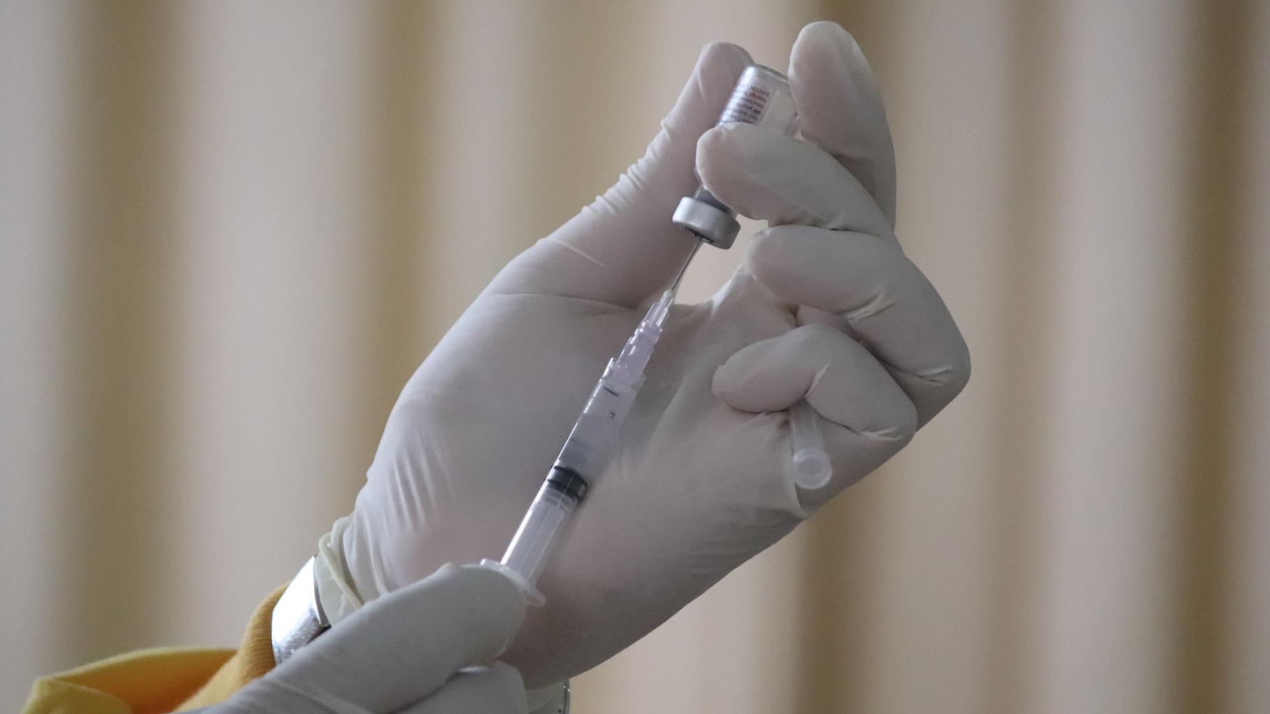 Nahaufnahme von Händen in Handschuhen beim Aufziehen einer Impfdosis