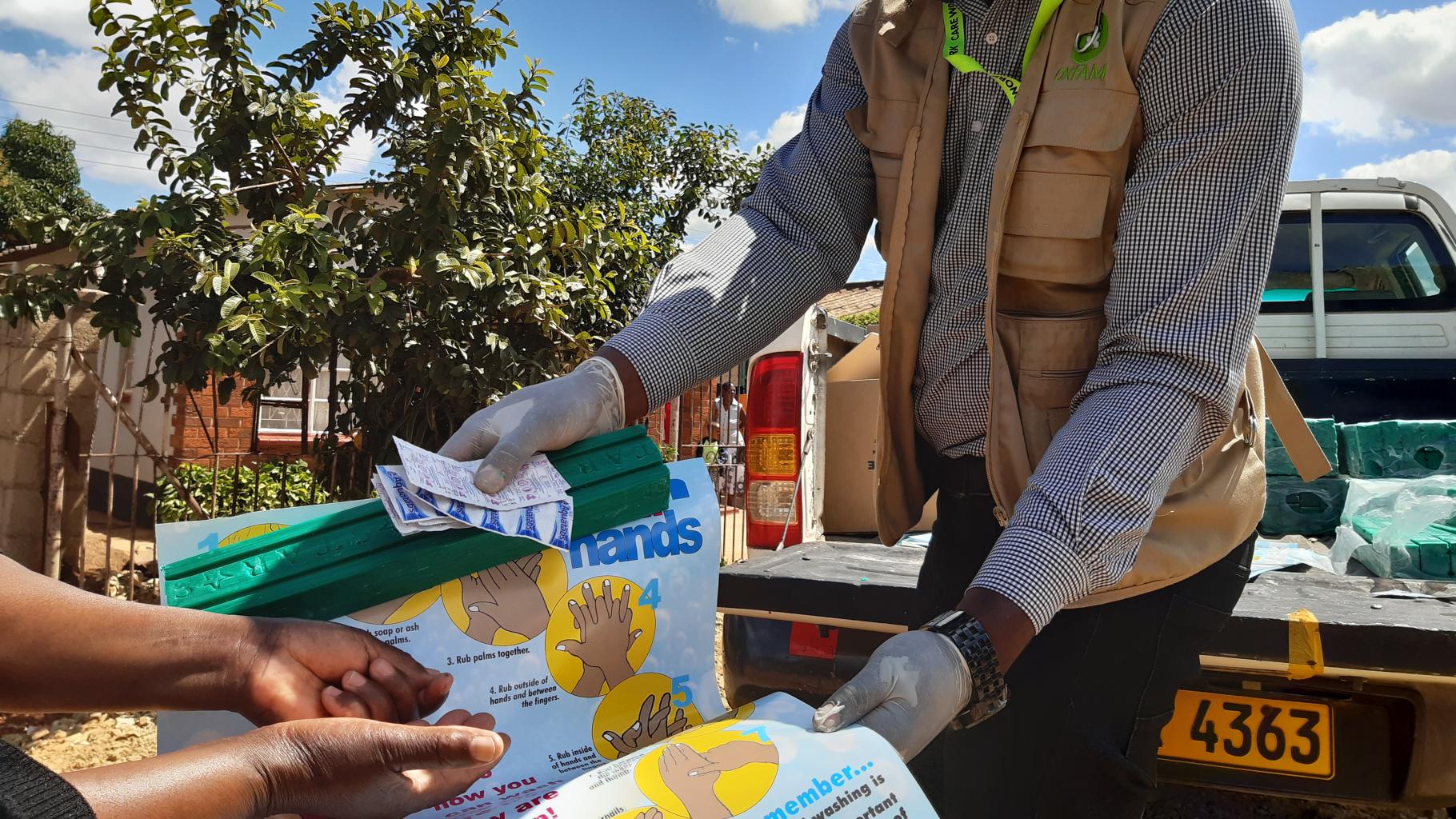 Oxfam-Mitarbeiter Munashe erklärt der Gemeinschaft in Harare, Simbabwe die Nutzung und Verwendung von Aqua-Tabs zur Wasseraufbereitung.