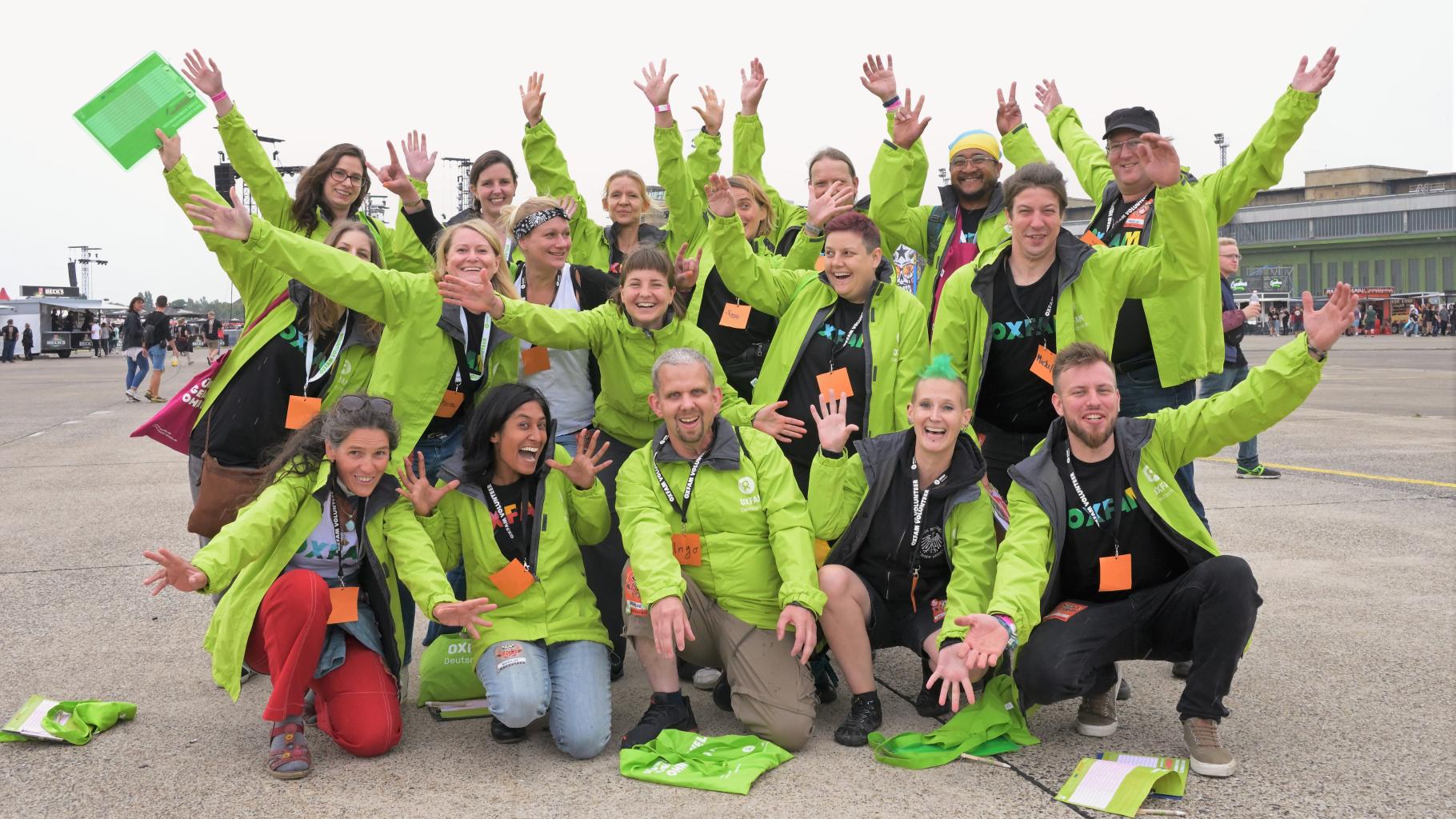 Gruppenfoto von Oxfam-Aktivist*innen bei einem Konzert der Toten Hosen auf dem Tempelhofer Feld. Alle tragen grüne Oxfam-Jacken und strecken ihre Arme in die Luft.