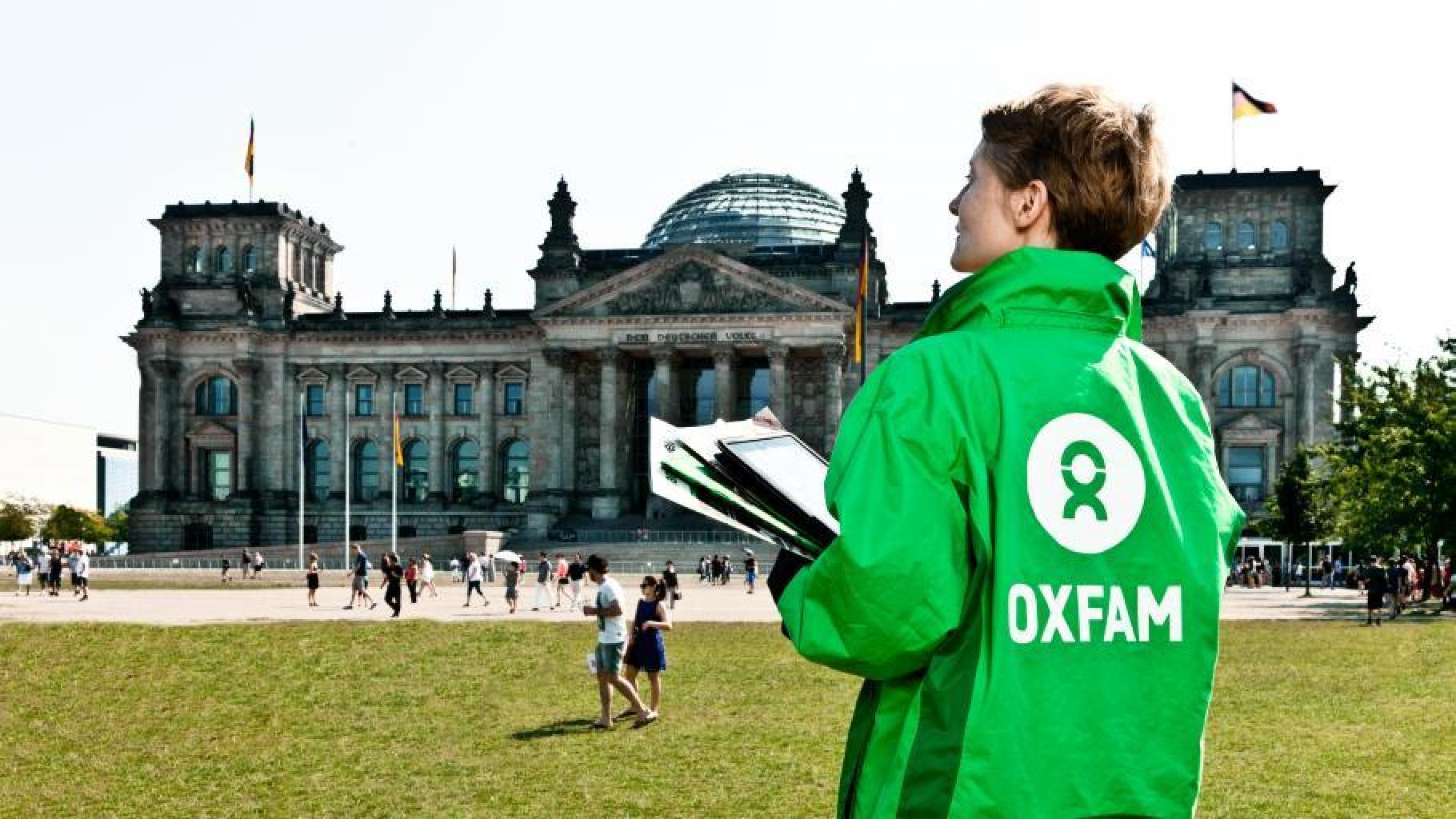 Eine Oxfam Mitarbeiterin steht mit Unterschriftenlisten vor dem Reichstagsgebäude in Berlin. 