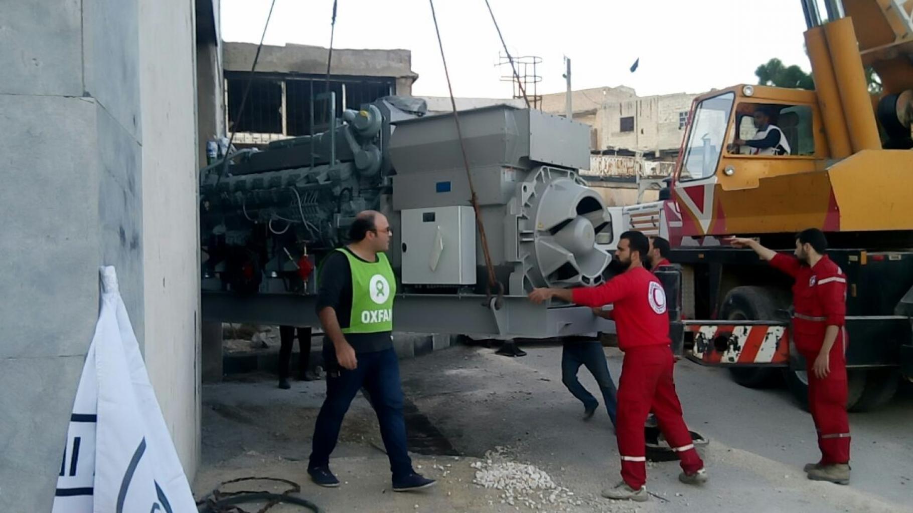 Mitarbeiter von Oxfam und des Roten Halbmonds entladen einen Generator