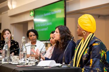 Annie Kelly, Hala Al Karib, Rasha Obaid, Preet Kaur Gill MP und Riya William Yuyada sitzen an einem Tisch mit Tischmikrophonen und tauschen sich vor einem Publikum aus