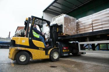 Corona-Nothilfe für Indien: Im Oxfam Versorgungszentrum in Bicester (Großbritannien) verlädt ein Gabelstapler Paletten mit Corona-Schutzausrüstung. Corona-Nothilfe für Indien: Eein Gabelstapler lädt Paletten mit Corona-Schutzausrüstung in einen LKW.