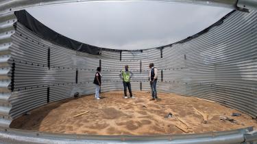 Blick in einen geplünderten und zerstörten Wassertank im Geflüchtetencamp in Rusayo. Ein riesiger Wassertank ist aufgeschnitten. In ihm stehen drei Menschen und schauen sich die Zerstörung an.