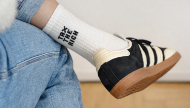 Eine Tennissocke mit der Aufschrift „Tax the Rich“ (Reiche besteuern) an einem Fuß.