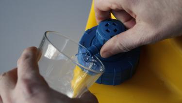 Ein Benutzer dreht den Wasserhahn des LifeSaver-Cubes auf.