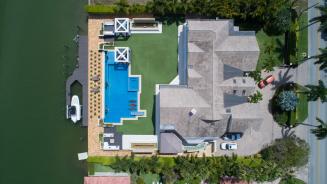 Luftaufnahme einer Villa mit Fuhrpark, Pool, Boot und Anlegestelle