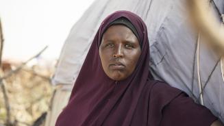 Eine Frau steht vor ihrer Behausung