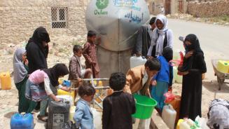 Frauen und Kinder holen Wasser an einem Tank in Khamir im Jemen.