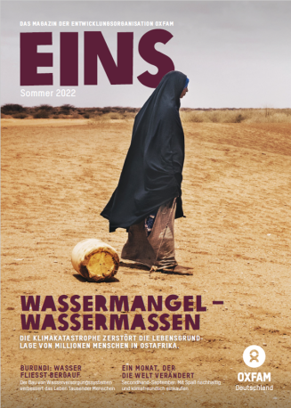 Titelbild der Sommerausgabe der EINS: Eine Frau mit dunklem Gewand läuft durch eine dürre Landschaft und zieht einen leeren Wasserbehälter hinter sich her