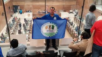 Gewerkschafter Didier Leitón steht in einer costa-ricanischen Institution und hält die Flagge seiner Gewerkschaft hoch.