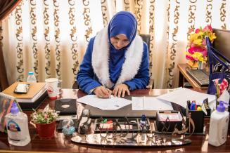 Asmaa Al Imamy sitzt an einem Schreibtisch und füllt ein Formular aus