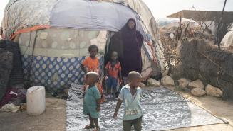 Layla Abdi Eige mit einigen ihrer Kinder vor ihrer Hütte Eine Frau steht mit einigen Kinder vor einer behelfsmäßigen Hütte