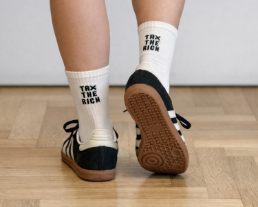 Tennissocken mit der Aufschrift „Tax the Rich“ (Reiche besteuern) an zwei Füßen.