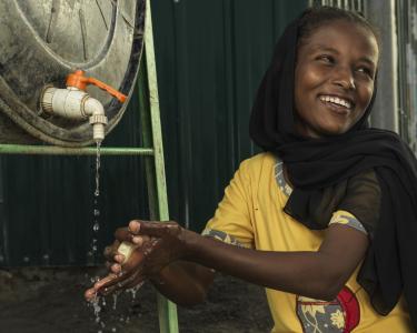 Ein Kind wäscht sich die Hände an einem Wassertank von Oxfam