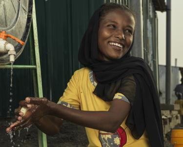 Ein Kind wäscht sich die Hände an einem Wassertank von Oxfam