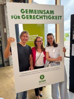 Drei Personen halten einen Rahmen mit der Aufschrift „Gemeinsam für Gerechtigkeit“.