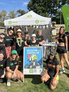 Eine Gruppe von Menschen steht vor einem Festivalstand von Oxfam