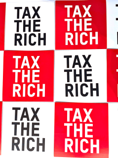 Ein Bild mit der Aufschrift "Tax the Rich" auf einem Schachmuster in rot und weiß.