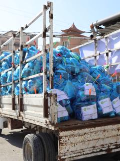 Ein rostiger Lastwagen transportiert mit Hilfsgütern gefüllte blaue Plastiksäcke