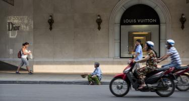 Mann sitzt vor Louis-Vuitton-Laden in Hanoi und bettelt