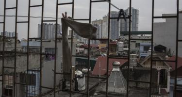 Von einer einkommensschwachen Gegend in Hanoi in Vietnam sieht man Hochhäuser in den Himmel ragen.