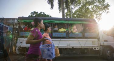 Nach der Schicht: Textilarbeiter/innen in Yangon auf dem Heimweg. Zwei Frauen gehen neben einem Bus