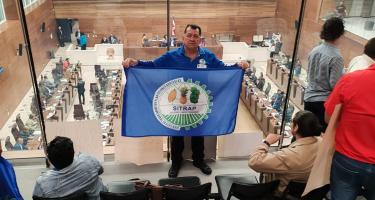 Gewerkschafter Didier Leitón steht in einer costa-ricanischen Institution und hält die Flagge seiner Gewerkschaft hoch.