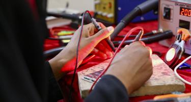 Die Mobilfunktechnikerin Nahla Abdo bei einer Reparatur in ihrer Werkstatt im Gouvernement Taiz im Jemen. Sie hat eine Weiterbildung bei unserer Partnerorganisation Tamdeen Youth Foundation absolviert. Nahla Abdo arbeitet mit einem Multimeter.