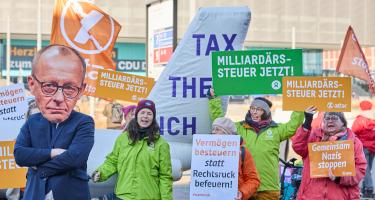 Eine Protest-Veranstaltung. Auf den Plakaten steht „Milliardärssteuer jetzt!“ und „Vermögen besteuern statt Rechtsruck befeuern!“
