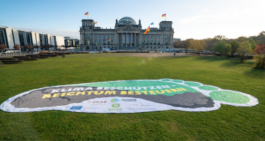 Überdemensionaler Fußabdruck als Tranparent auf der Wiese vor dem Reichstagsgebäude. Es trägt die Aufschrift "Klima beschützen - Reichtum bestuern"