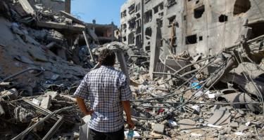 Mann steht vor zerstörten Haus im Gazastreifen Ein palästinensicher Mann steht vor einem durch israelische Bombenangriffe zerstörten Haus in Gaza
