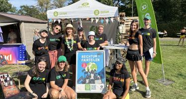 Gruppenbild Lollapalooza 2024 Eine Gruppe von Menschen steht vor einem Festivalstand von Oxfam