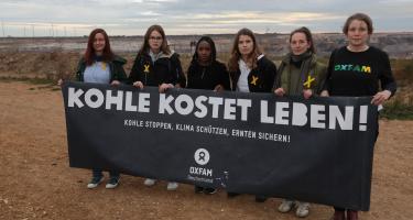 Elizabeth Wathuti (3. v.l.), Luisa Neubauer (4. v.l.) und andere Aktivist*innen an der Abbruchkante des Braunkohletagebaus im nordrhein-westfälischen Lützerath. Sechs Frauen stehen mit einem schwarzen Banner in der Hand am Rand des Tagebaus Garzweiler. Auf dem Banner steht: Kohle kostet leben! Kohle stoppen, Klima schützen, Ernten sichern!