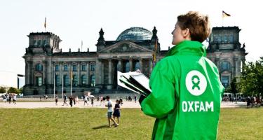 Oxfam setzt sich bei Politik und Wirtschaft für eine gerechte Welt ohne Armut ein. Eine Oxfam Mitarbeiterin steht mit Unterschriftenlisten vor dem Reichstagsgebäude in Berlin.