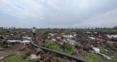Zerstörte Wasserleitung in einem verlassenen und verwüsteten Camp für Geflüchtete in Rusayo. Zerwühlter Boden, Müll und dazwischen eine Wasserleitung, die eigentlich unter der Erde verlaufen sollte. Das Geflüchtetencamp in Rusayo ist verwüstet.