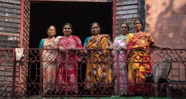 Ein eigenes Einkommen ermöglicht Frauen ein selbstbestimmteres Leben. Frauen in bunten Saris stehen auf einem Balkon und lächeln in die Kamera