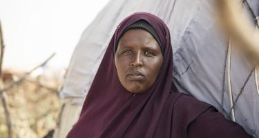 Eine Frau steht vor ihrer Behausung