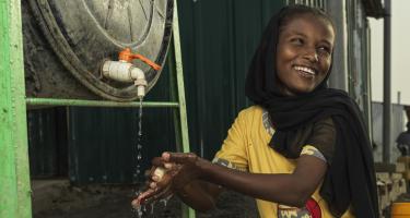 Ein Kind wäscht sich die Hände an einem Wassertank von Oxfam