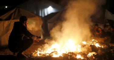 Geflüchteter in Griechenland vor einem Feuer