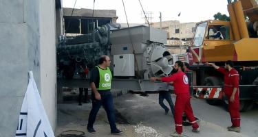 Mitarbeiter von Oxfam und des Roten Halbmonds entladen einen Generator