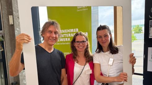 Drei Personen halten einen Rahmen mit der Aufschrift „Gemeinsam für Gerechtigkeit“.