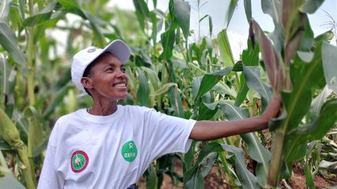 Clémence Nibaruta steht stolz in ihrem Maisfeld in Gitega, Burundi. Sie hat an Schulungen unserer Partnerorganisation ADISCO in Gitega (Burundi) teilgenommen und betreibt nun agrarökologischen Landbau.